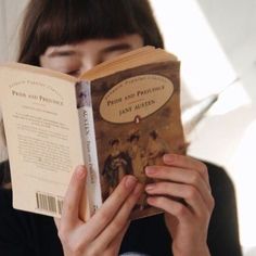 a woman is reading a book in front of her face