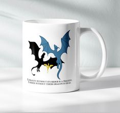 a white coffee mug with blue and black dragon designs on it