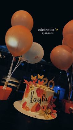 a birthday cake with orange balloons and congratulations written on it in front of a black background