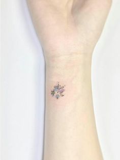 a small star and moon tattoo on the wrist