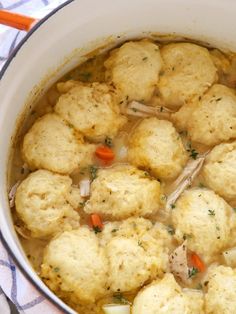 a pot filled with soup and dumplings on top of a table cloth next to an orange spoon