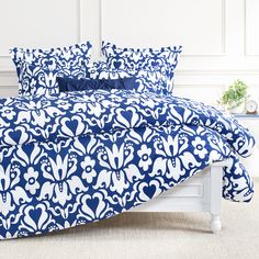 a bed with blue and white comforters on it in front of a white wall