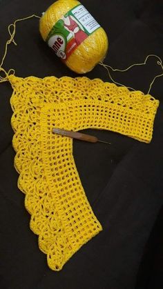 a yellow crochet piece next to a ball of yarn and a pair of scissors