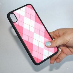 a woman's hand holding an iphone case with pink and white squares on it