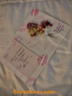 two greeting cards with flowers and writing on them are laying on a bed sheet that has been made to look like lips