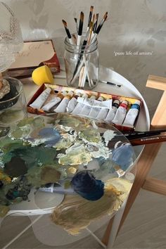 an artist's desk with paint and brushes on it