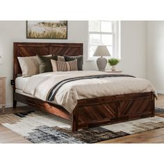 a bed sitting on top of a wooden floor next to a dresser and lamp in a bedroom