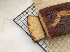 a loaf of bread sitting on top of a cooling rack next to a piece of cake