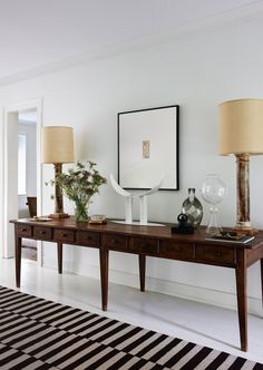 a table with two lamps on top of it next to a rug and lamp shades