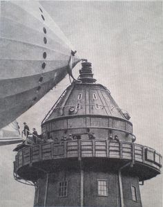 an old black and white photo of people on the top of a building next to a large balloon