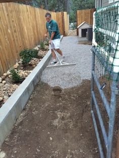 a man with a mop is cleaning the ground in front of a fenced yard