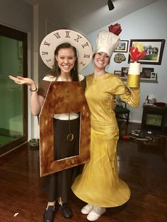 two women dressed up in costumes posing for a photo with a clock on their face