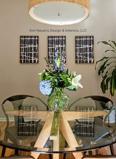 a glass table topped with a vase filled with blue and white flowers on top of a hard wood floor