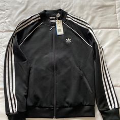 Adidas Women Superstar Three Stripe Track Jacket Black Size Medium New With Tags Casual Black Varsity Jacket With Zipper, Black Casual Varsity Jacket With Zipper, Casual Black Varsity Jacket With Zipper Closure, Black Casual Varsity Jacket With Zipper Closure, Adidas Long Sleeve Outerwear With Three Stripes, Black Outerwear With Three Stripes For Fall, Adidas Three Stripes Fall Outerwear, Adidas Black Outerwear With Three Stripes Branding, Adidas Outerwear With Three Stripes For Fall