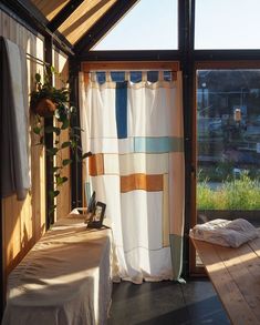 a room with a bed and curtains in it, next to a window that looks out onto the yard