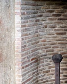 an old metal pole in front of a brick wall