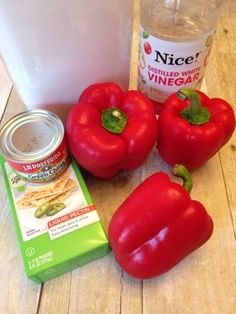 three red bell peppers next to a can of vinegar and some other ingredients on a wooden table