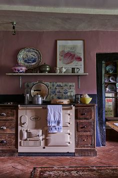 an old fashioned stove in the corner of a room with pink walls and wooden floors