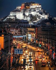 a city street filled with lots of traffic under a tall white mountain covered in snow