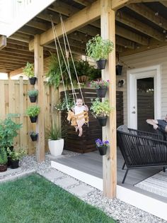 a person sitting on a porch swing with potted plants hanging from the ceiling above