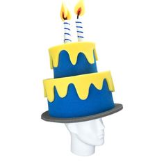 a blue and yellow birthday cake with two candles on it's top, in front of a white mannequin head