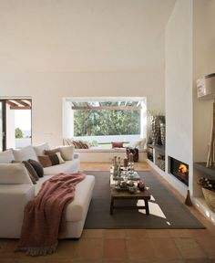 a living room filled with furniture and a fire place under a window next to a fireplace