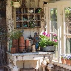 an old table with potted plants on it in front of a window sill