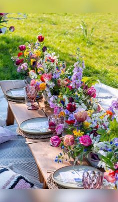 a long table with plates and vases filled with colorful flowers on top of it