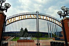 the entrance to michigan stadium is shown through an iron gate with lights on either side