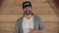 a man wearing a boom hat gives the thumbs up sign while standing in front of a wooden wall