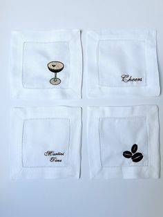 four white napkins with black embroidered designs on them, one has a wine glass and the other has an espresso