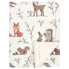 a blanket with animals on it next to a wooden stump and tree branch print in white