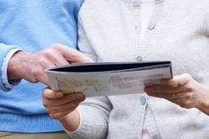 two people sitting next to each other while looking at something on a piece of paper