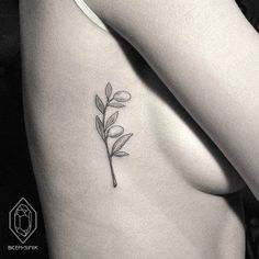 a woman's breast with a small flower tattoo on her left side ribcage