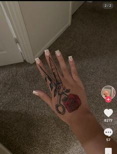 a person's hand with scissors and roses on it