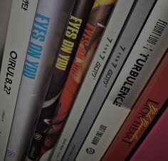 a bunch of books that are sitting on top of each other in front of a shelf