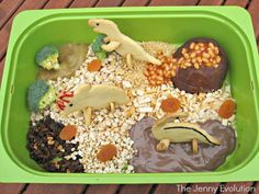 a green container filled with lots of different types of toys and food in it on top of a wooden table