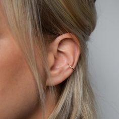 a close up of a woman's ear with a single diamond in the middle