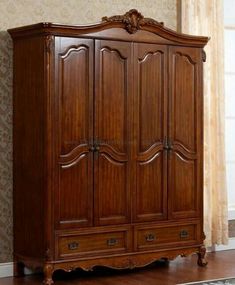 a large wooden armoire sitting on top of a hard wood floor next to a window