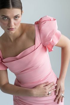 a woman in a pink dress is holding her stomach