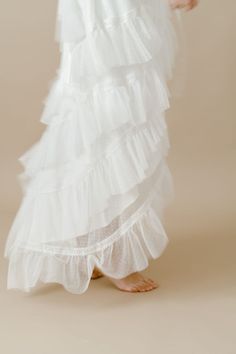 a woman wearing a white dress with ruffled layers