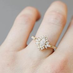 a woman's hand with a diamond ring on top of her finger, wearing a gold band