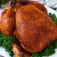 a whole chicken sitting on top of a white plate covered in parsley and garnish