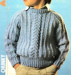 a young boy wearing a blue sweater and tan pants with his hands in his pockets