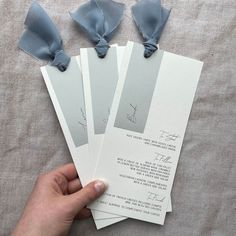 the person is holding four pieces of paper with blue bows on them, which are attached to each other