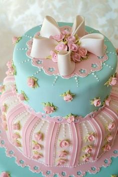 a blue cake with pink flowers and bows on top