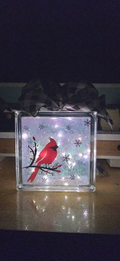 a glass block with a cardinal on it and snowflakes in the back ground