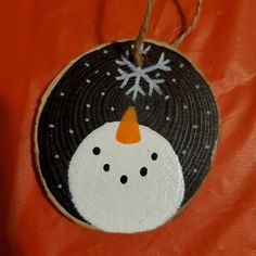 a snowman ornament hanging from a string on an orange leather jacket,