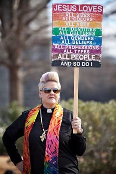 a woman holding a sign that says jesus loves altars all genderers all professions all people and so do