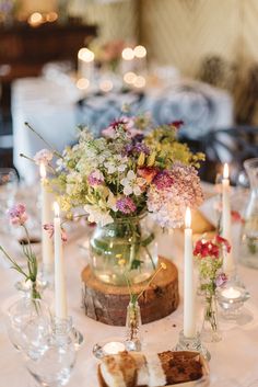 the table is set with candles and flowers in glass vases on top of it